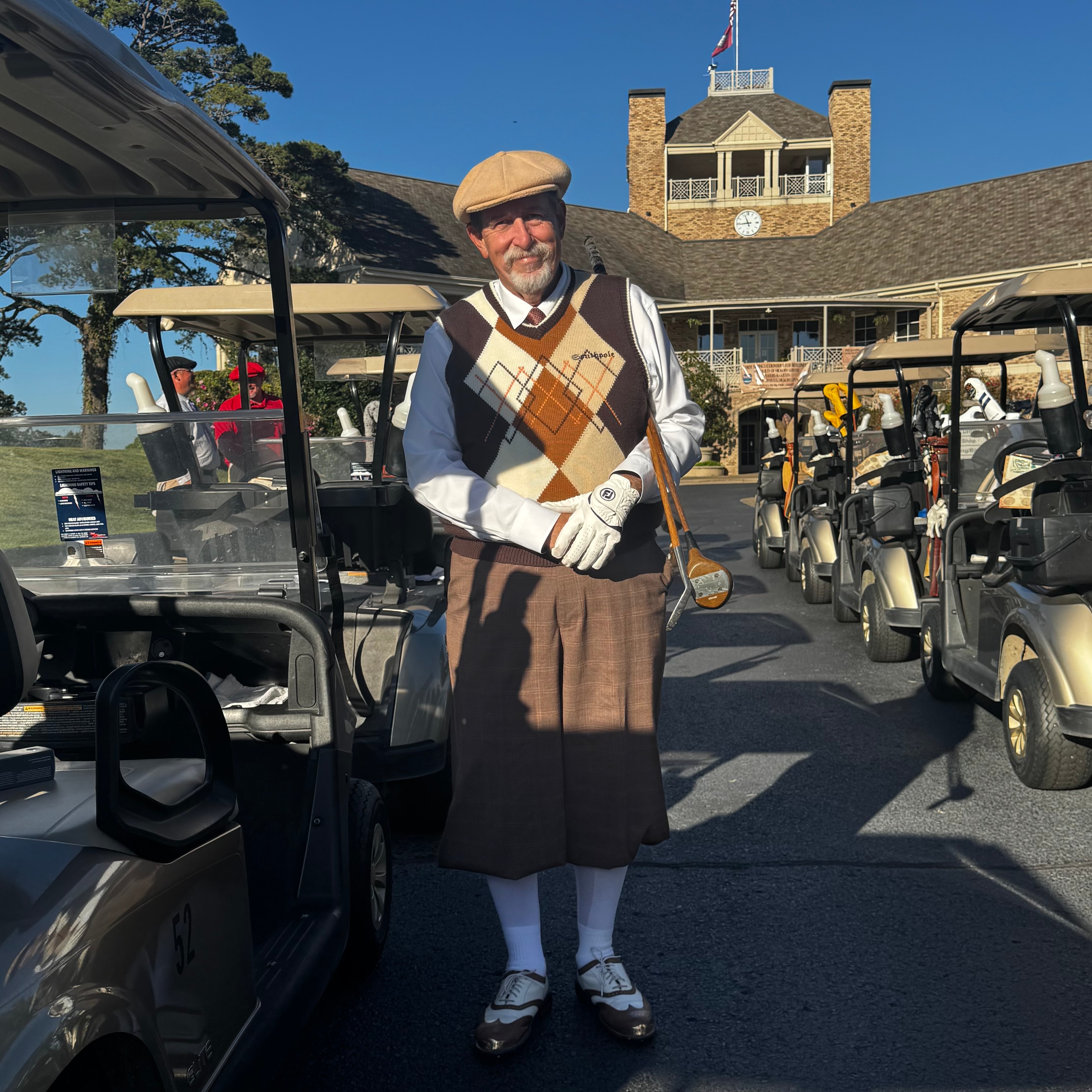 Golfer in vintage argyle vest and plus fours holding a hickory club