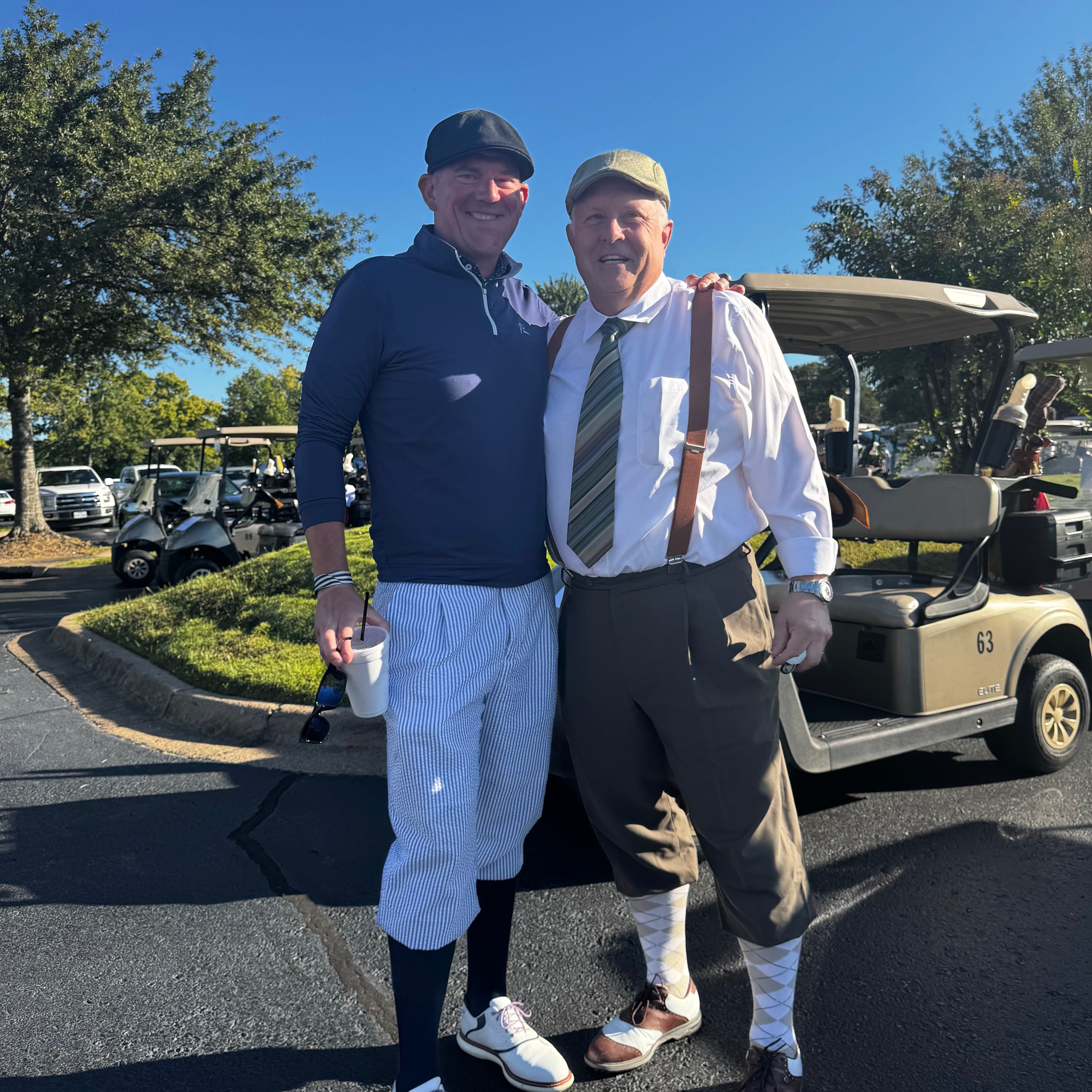 Two golfers in period attire sharing a moment of camaraderie